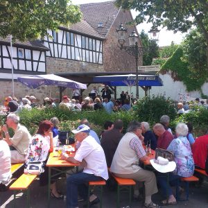 Gut besuchter Dorfplatz bei einem früheren Jazz Konzert an einem sommerlichen Vormittag, dazu passend